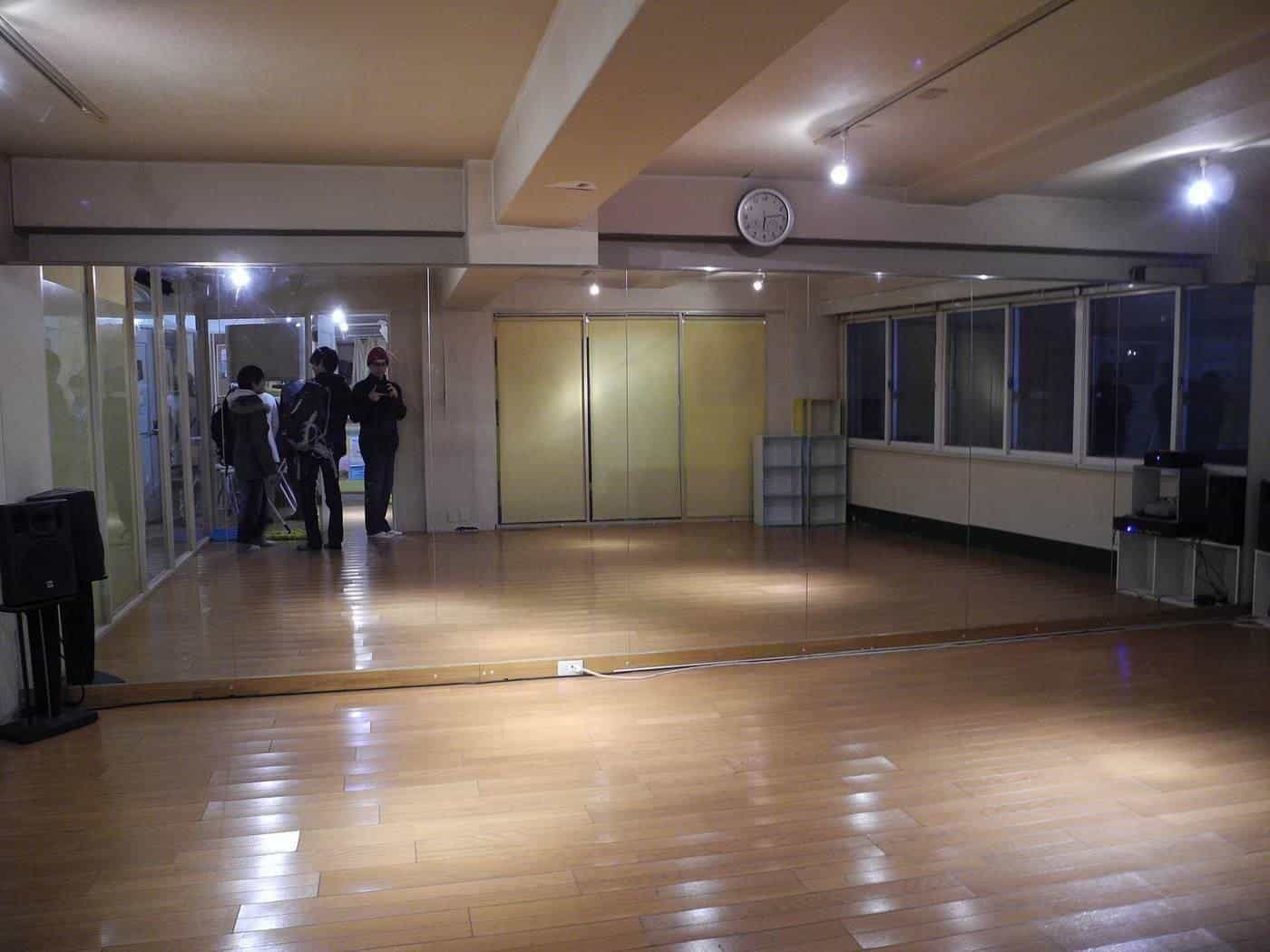 An empty dance studio with a wooden floor and wall mirror