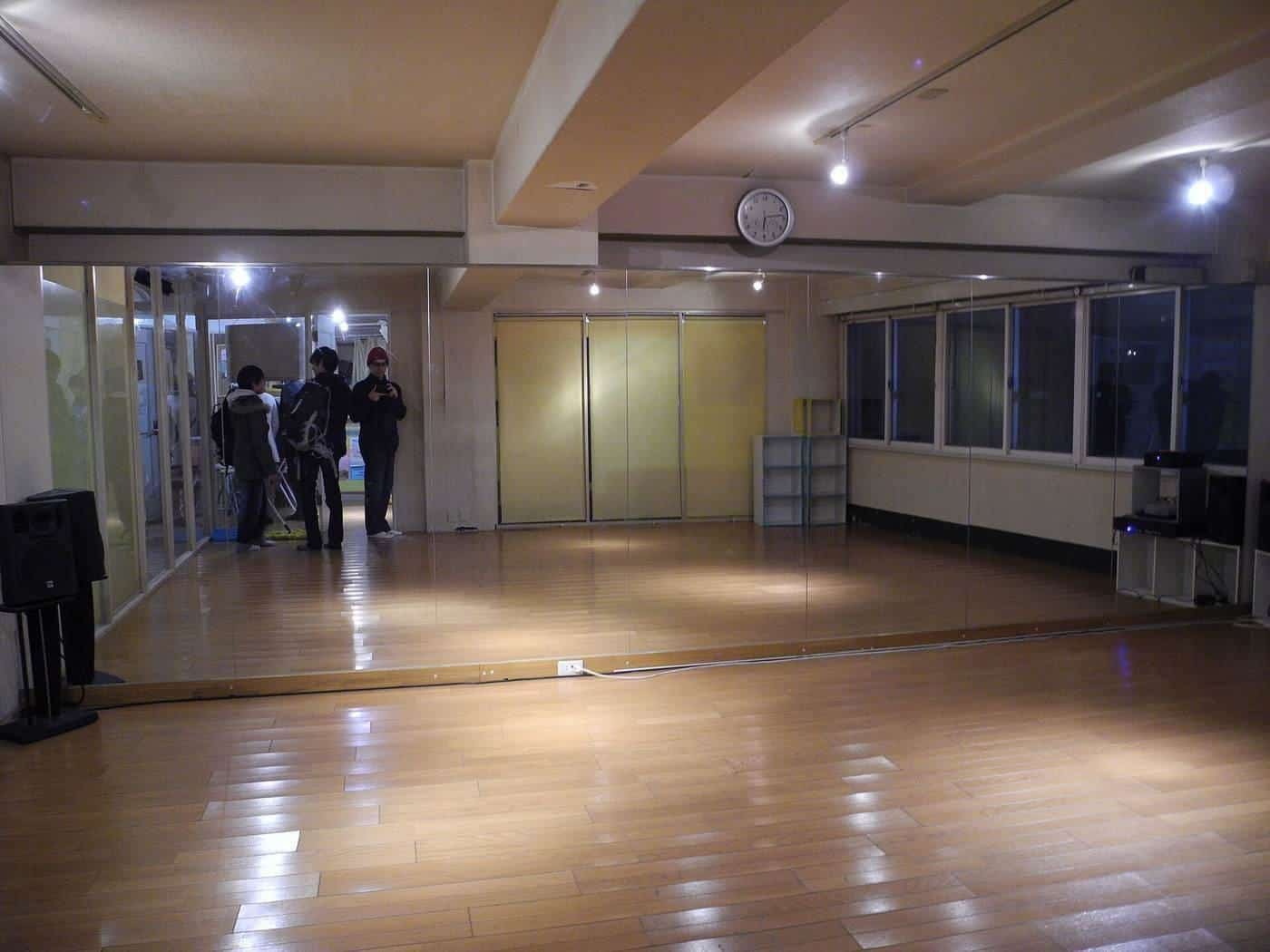 An empty dance studio with a wooden floor and wall mirror