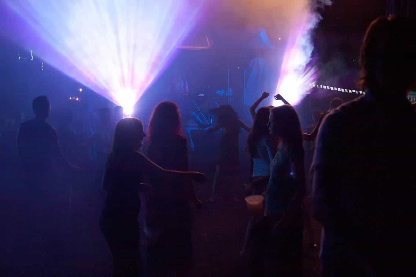 A crowd dancing at a night party under bright lights