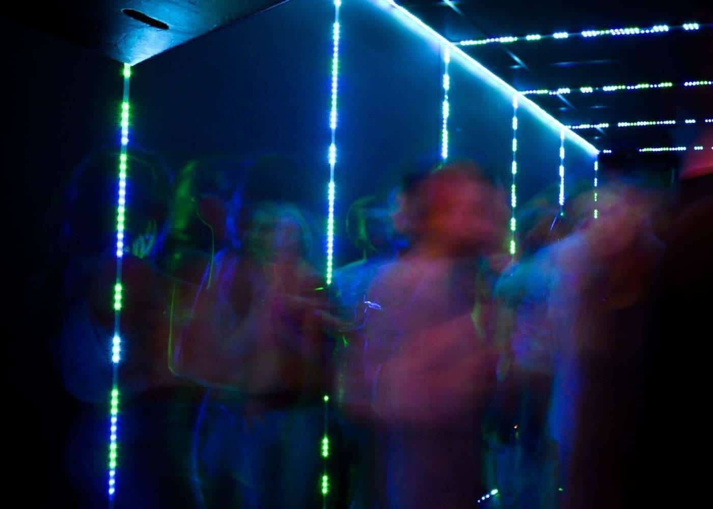 A dance floor lit with colourful neon lights and blurred dancers